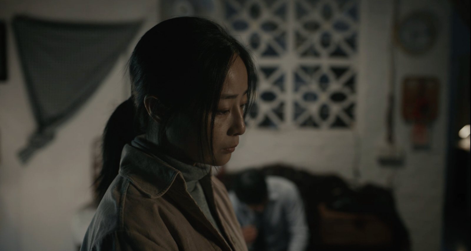Still from Museum of Death: a soul among weathered objects and falling dust in a dim museum space